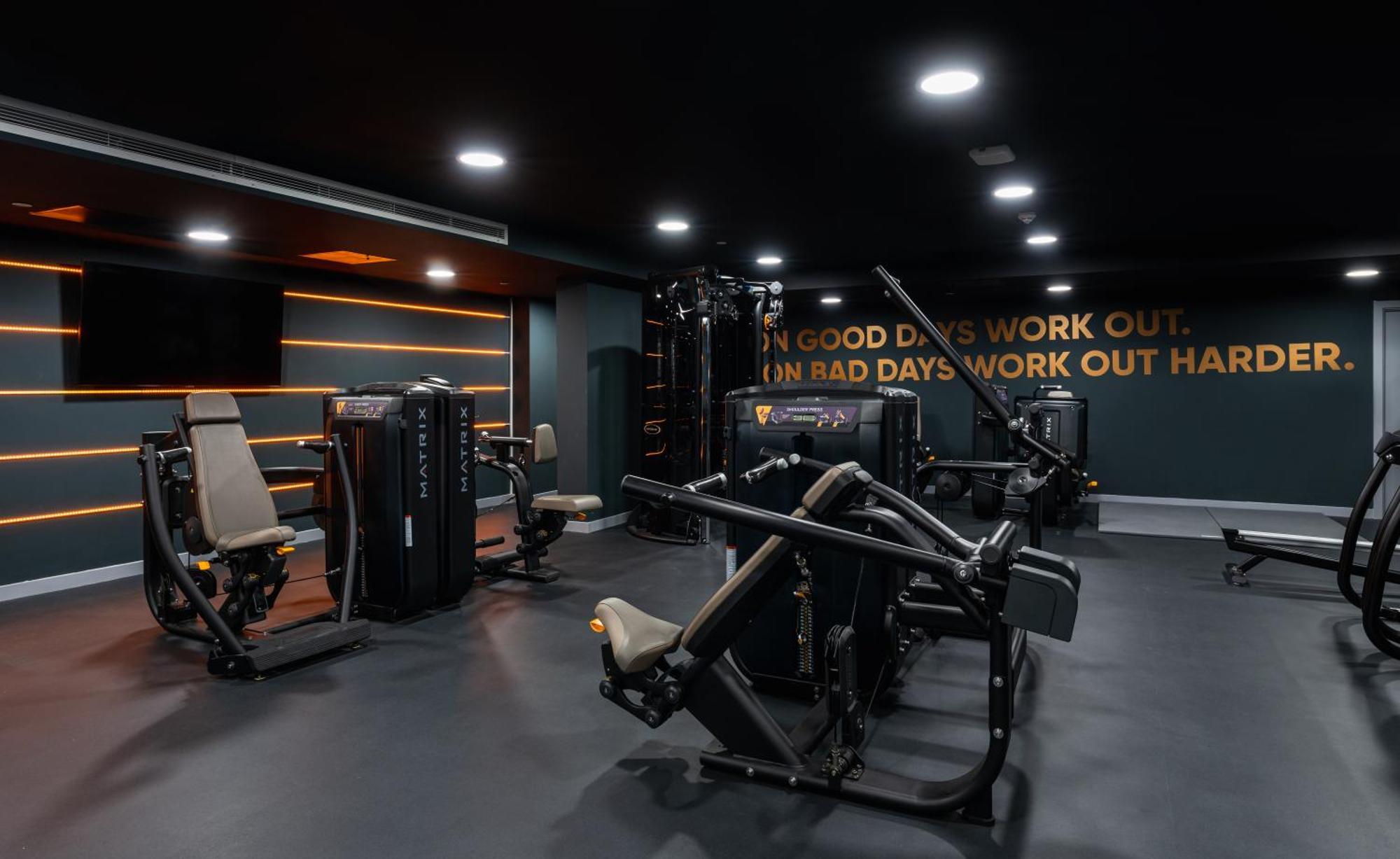 Citysuites 2 Aparthotel Salford (Greater Manchester) Exterior foto The photo shows a modern gym interior. The gym features various exercise machines, including weight training equipment. The flooring is dark, and the walls are adorned with motivational text that reads, "ON GOOD DAYS WORK OUT. ON BAD DAYS WORK OUT HA